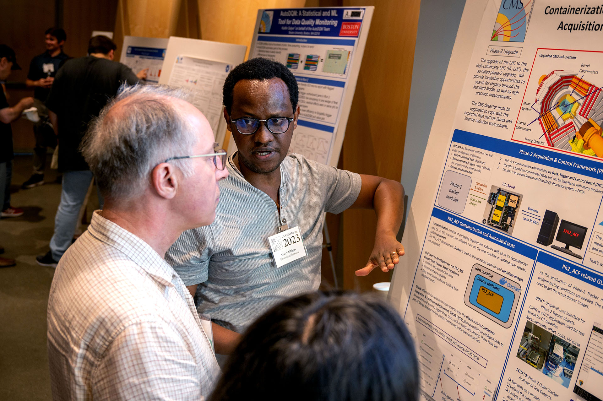 Student wearing eyeglasses presenting a research poster, standing beside the display and engaging viewers with an explanation of their work.