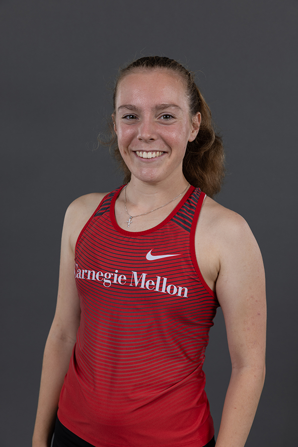 A young athlete smiling confidently, dressed in a red-purple Carnegie Mellon athletic top, posed for a portrait against a neutral background.