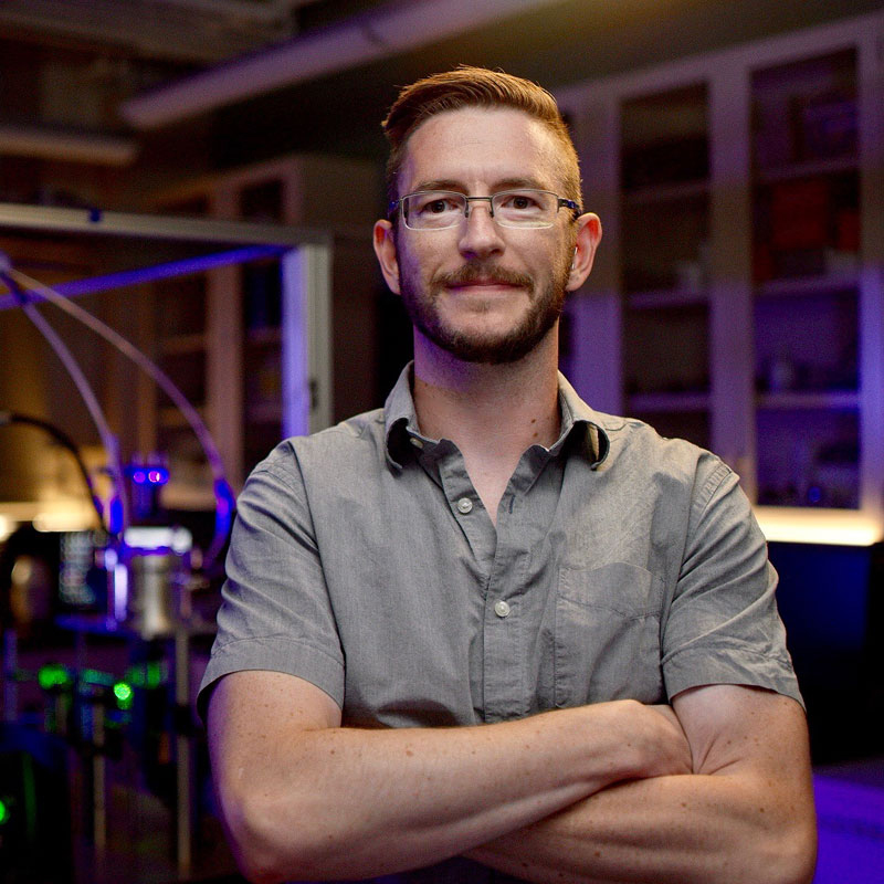 Ryan Sullivan stands in his lab and smiles at the camera.