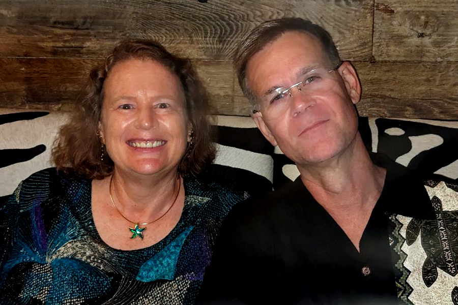 Susan Campbell and Scott Byer sit together and smile at the camera.