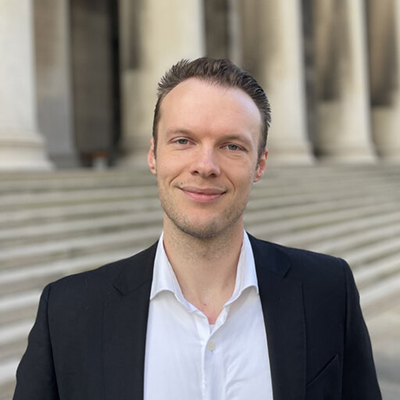 Dylan Anstine stands outside of Mellon Institute and smiles at the camera.