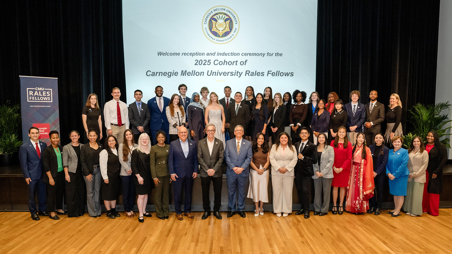 The 2025 cohort of Rales Fellows stand with Farnam Jahanian, Joshua Rales and Jim Garrett. All of them look into the camera and smile.
