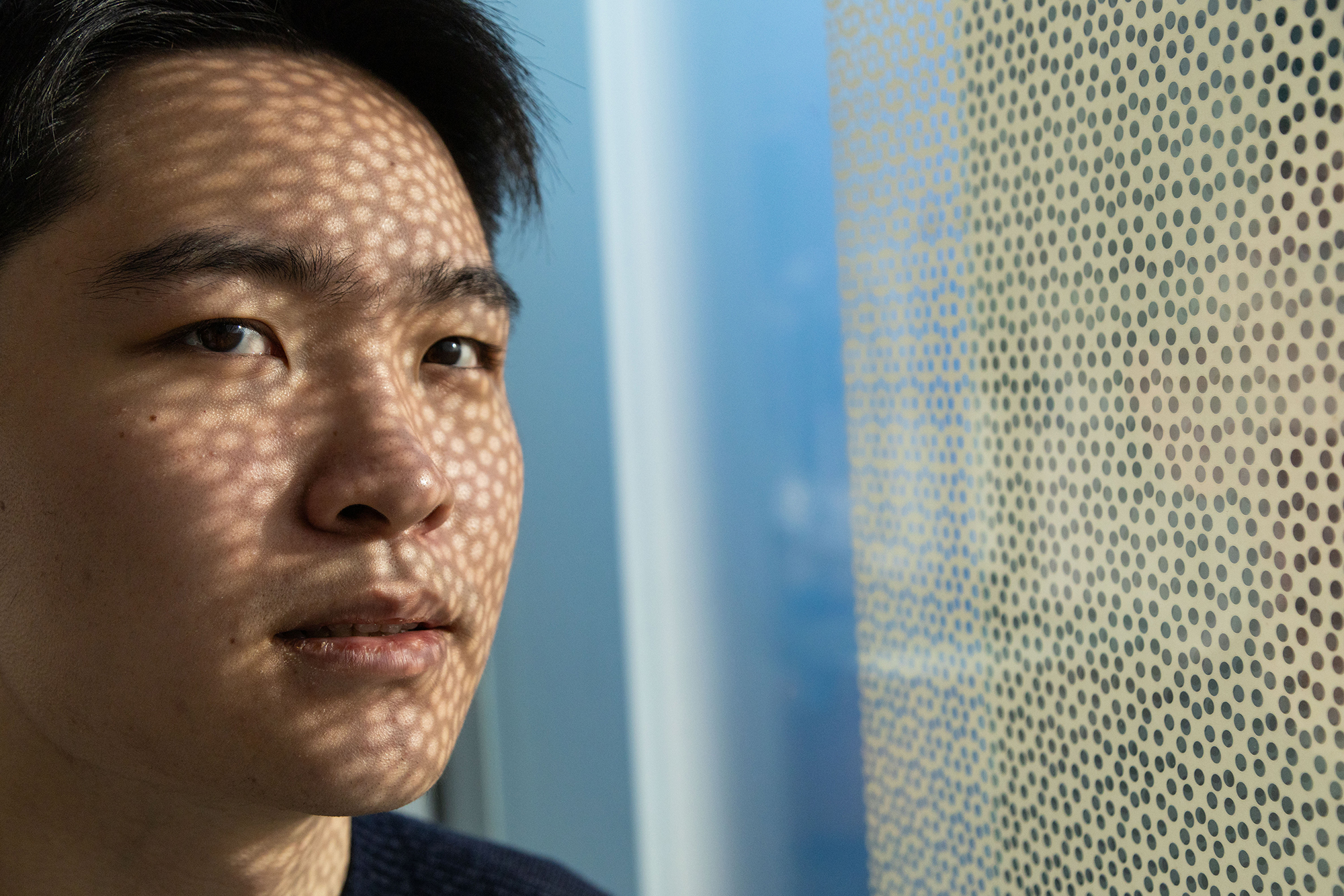 Zixi (Alan) Song looks into the camera. He has a pattern of dots of light on his face.