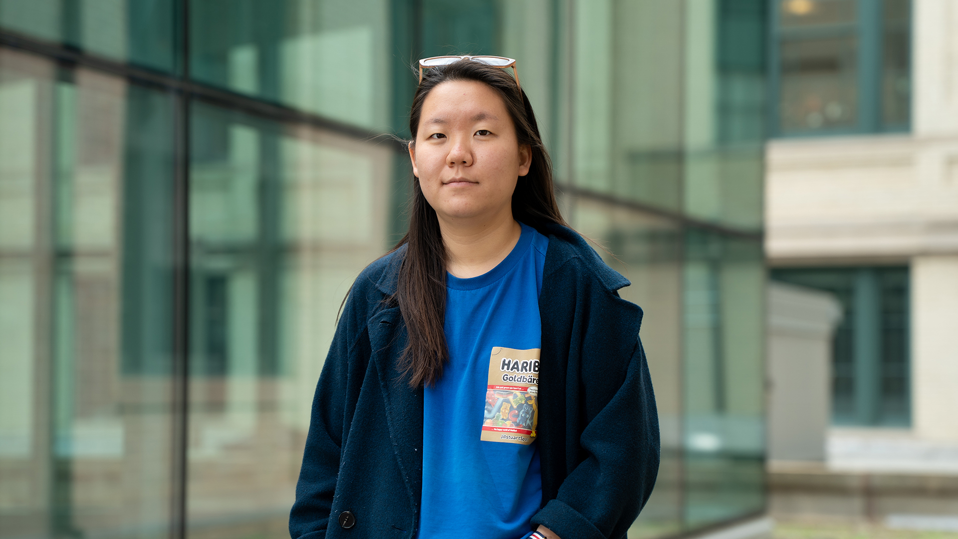 Kyungmin Park stands outside of a glass building. She smiles at the camera.