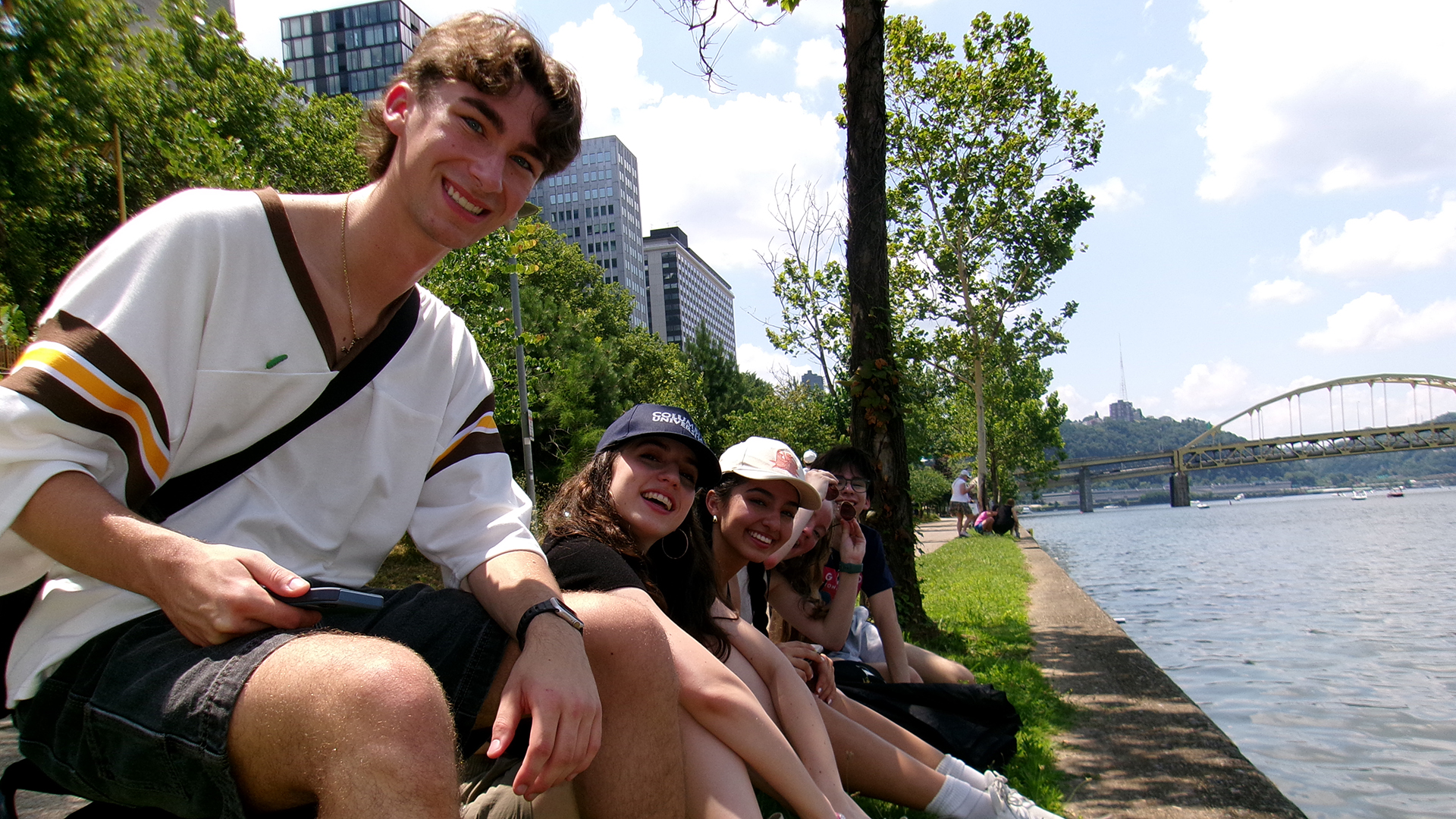 Students sit by the river.