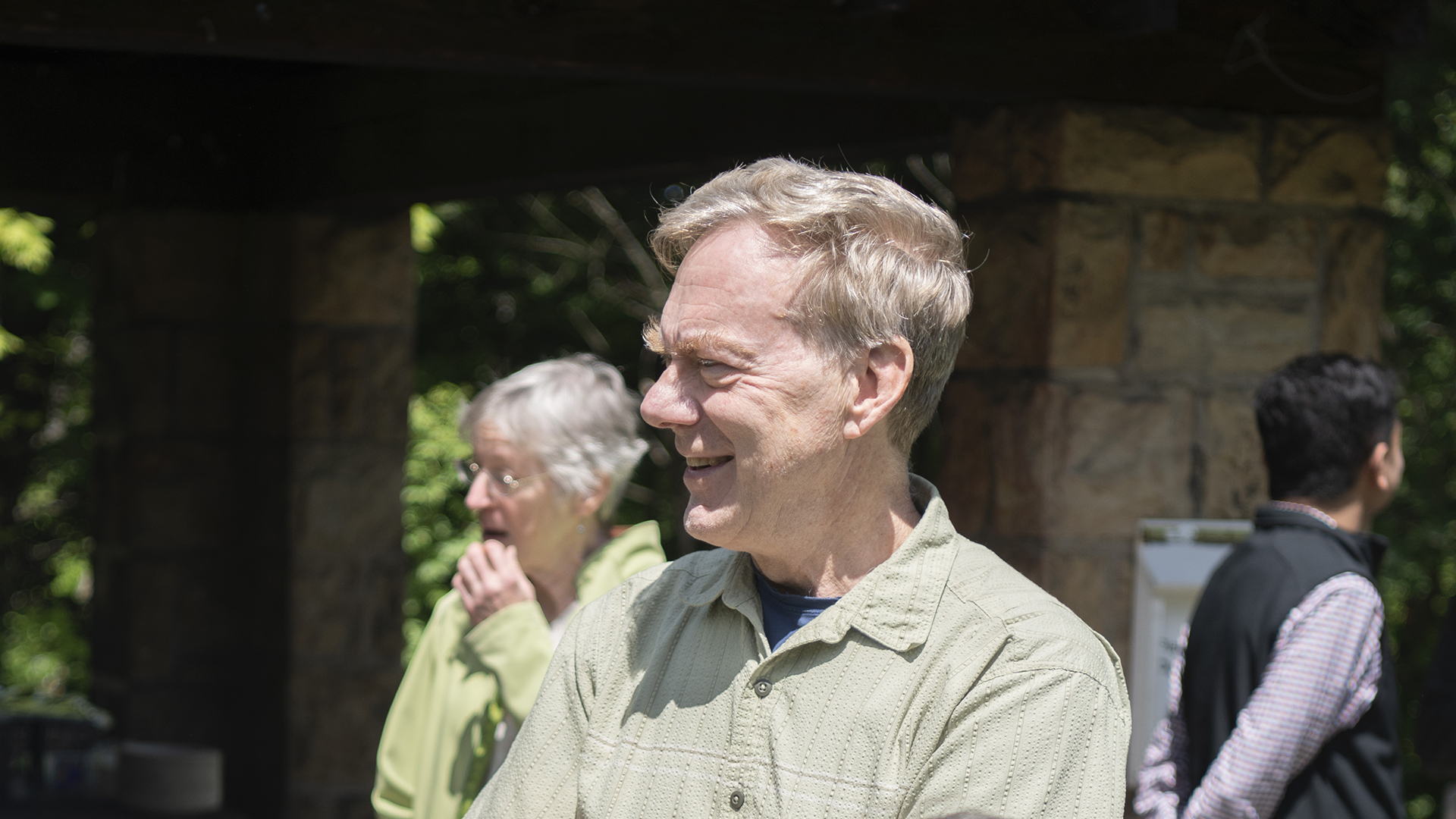 Michael Hendrich stands outside during a retirement party. He smiles at someone off camera.
