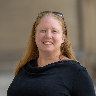 Luisa Hiller stands outside of Mellon Institute. She smiles at the camera.