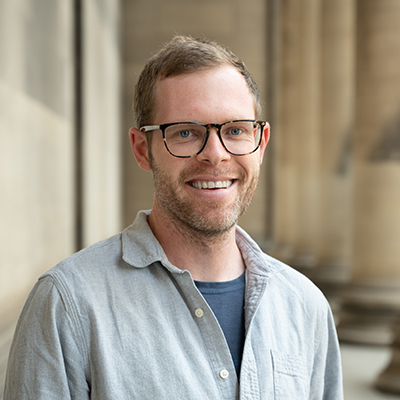 Drew Bridges stands outside of Mellon Institute. He smiles at the camera.