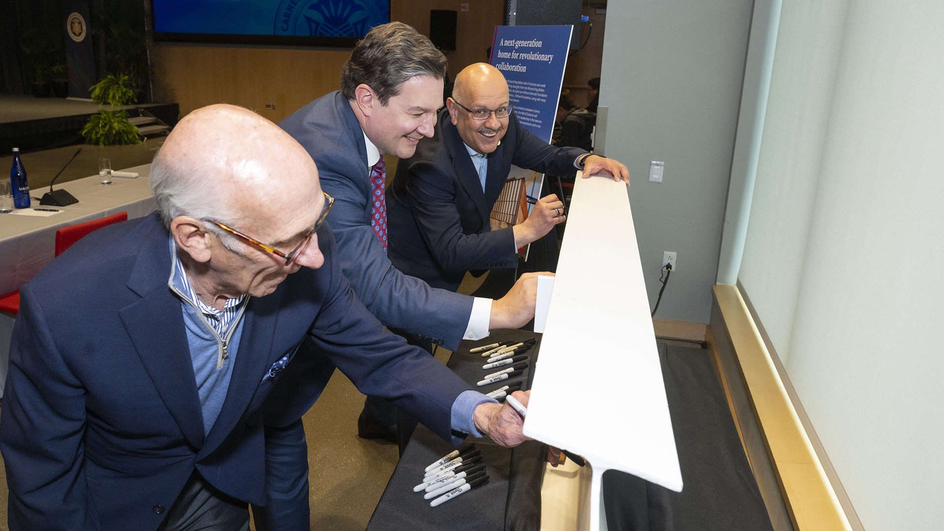 Chair of CMU's Board of Trustees David Coulter, Director of the Richard King Mellon Foundation Sam Reiman and CMU President Farnam Jahanian sign a beam for the Richard King Mellon Hall of Sciences, on Saturday, May 9, 2026, outside the Simmons Auditorium.