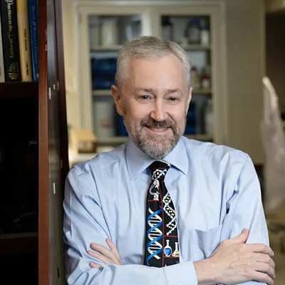 Bruce Armitage stands in an office and smiles at the camera.