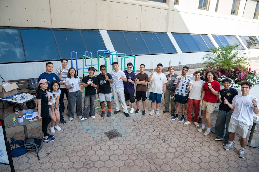 Group of students gathered outdoors on the CMU campus, standing together and smiling in a campus setting.
