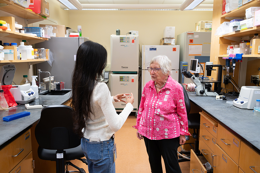 Student and professor discuss research work in a chemistry lab surrounded by scientific equipment and instruments.