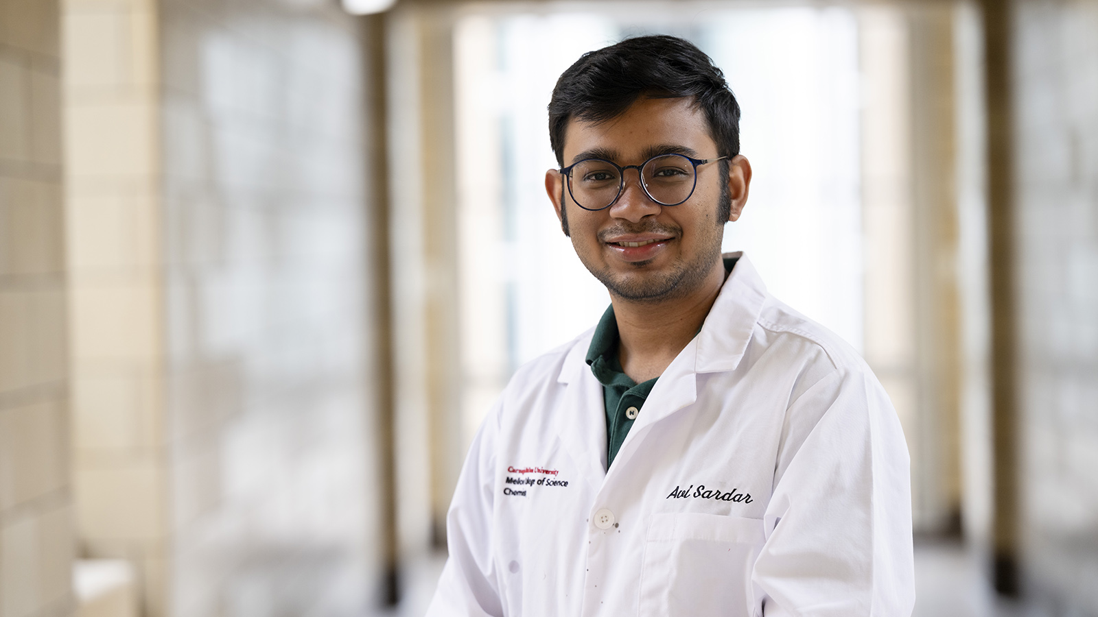 Avirup Sardar wears a white lab coat and smiles at the camera.