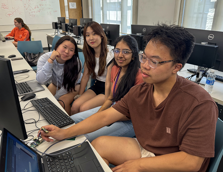 Four students sit in front of a computer