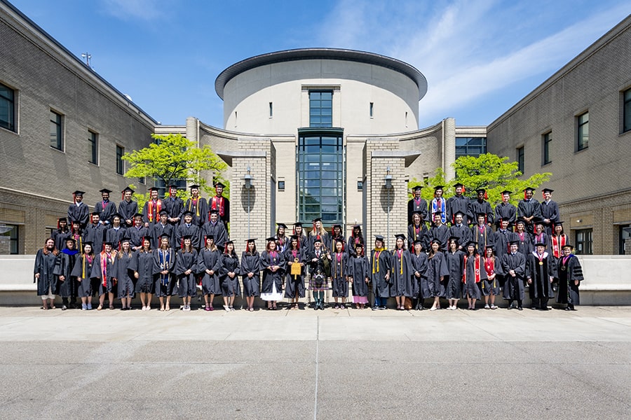 Group of students inducted into PBK posing in front of a building with circular roof.