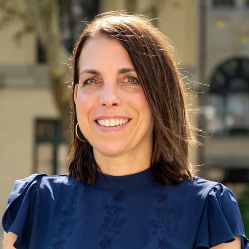 Rachel Rosenfeld - brunette white woman wearing a high-necked dark blue blouse