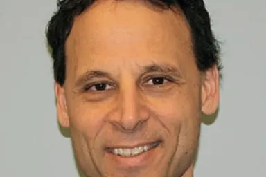 Ira Rothstein - headshot of a man with short dark wavy hair and brown eyes