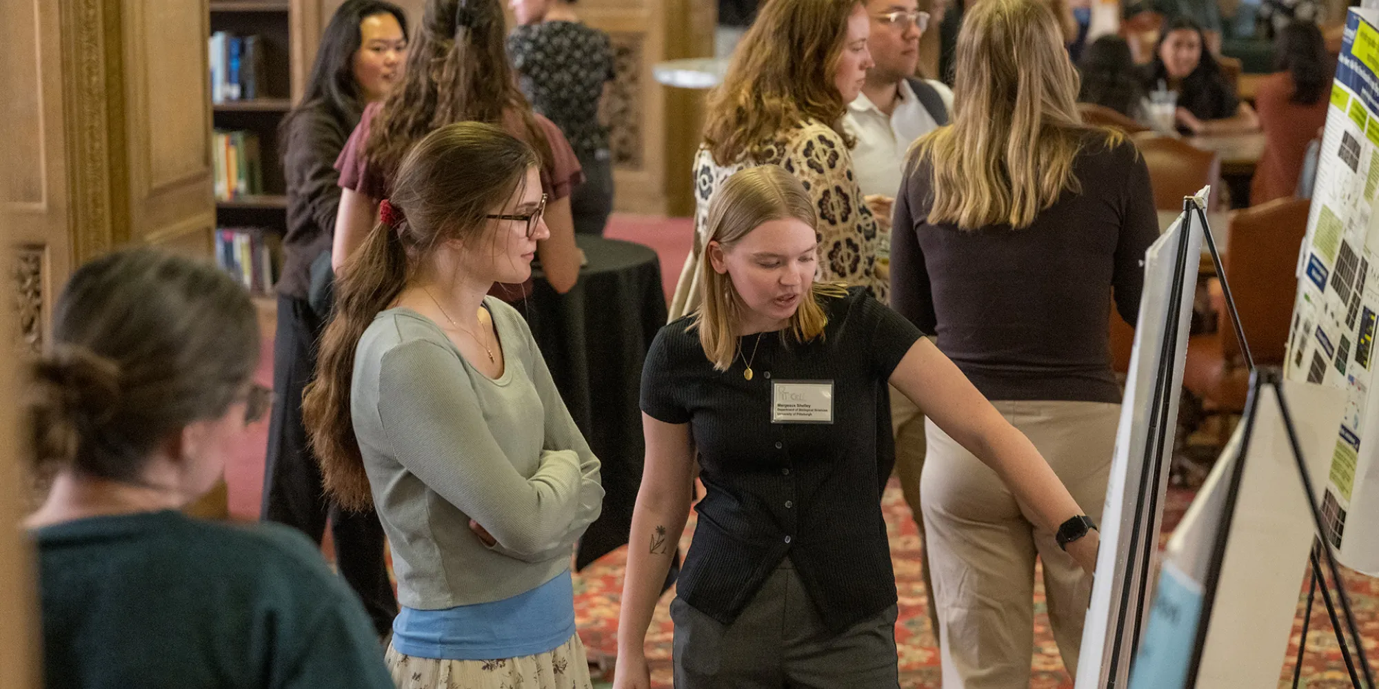 Conference attendees viewing and discussing research posters during a poster session at the Pittcell Conference.