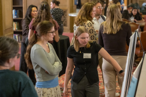Conference attendees viewing and discussing research posters during a poster session at the Pittcell Conference.