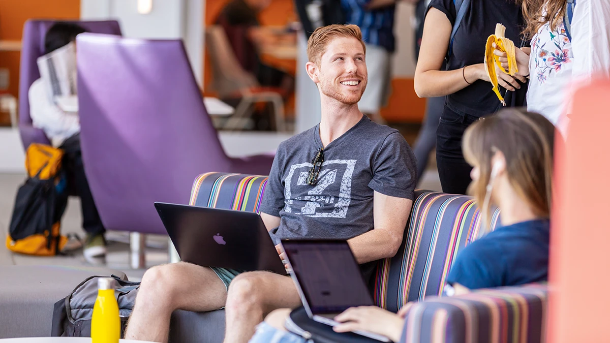 A student sitting on a couch with a laptop