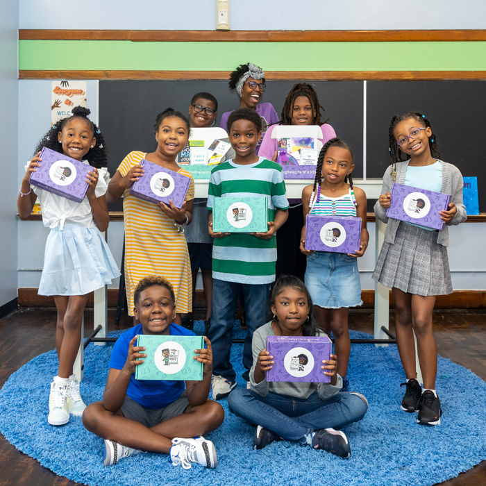 A group of children pose with kit boxes