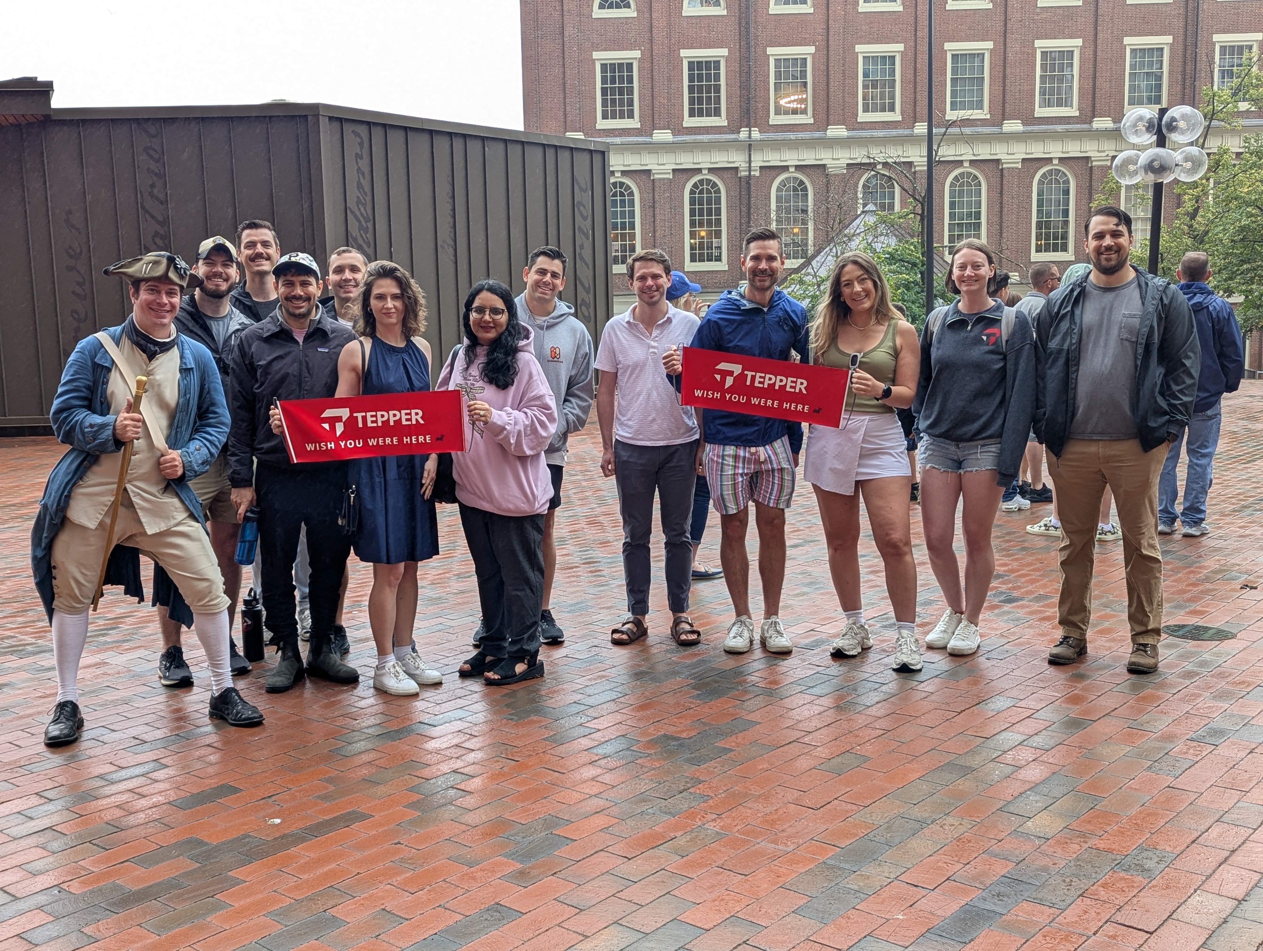 Group posing with Tepper Wish You Were Here banners