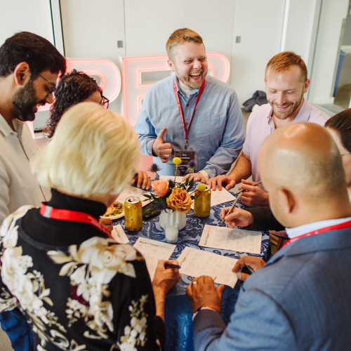 A group of alumni standing around a table smiling