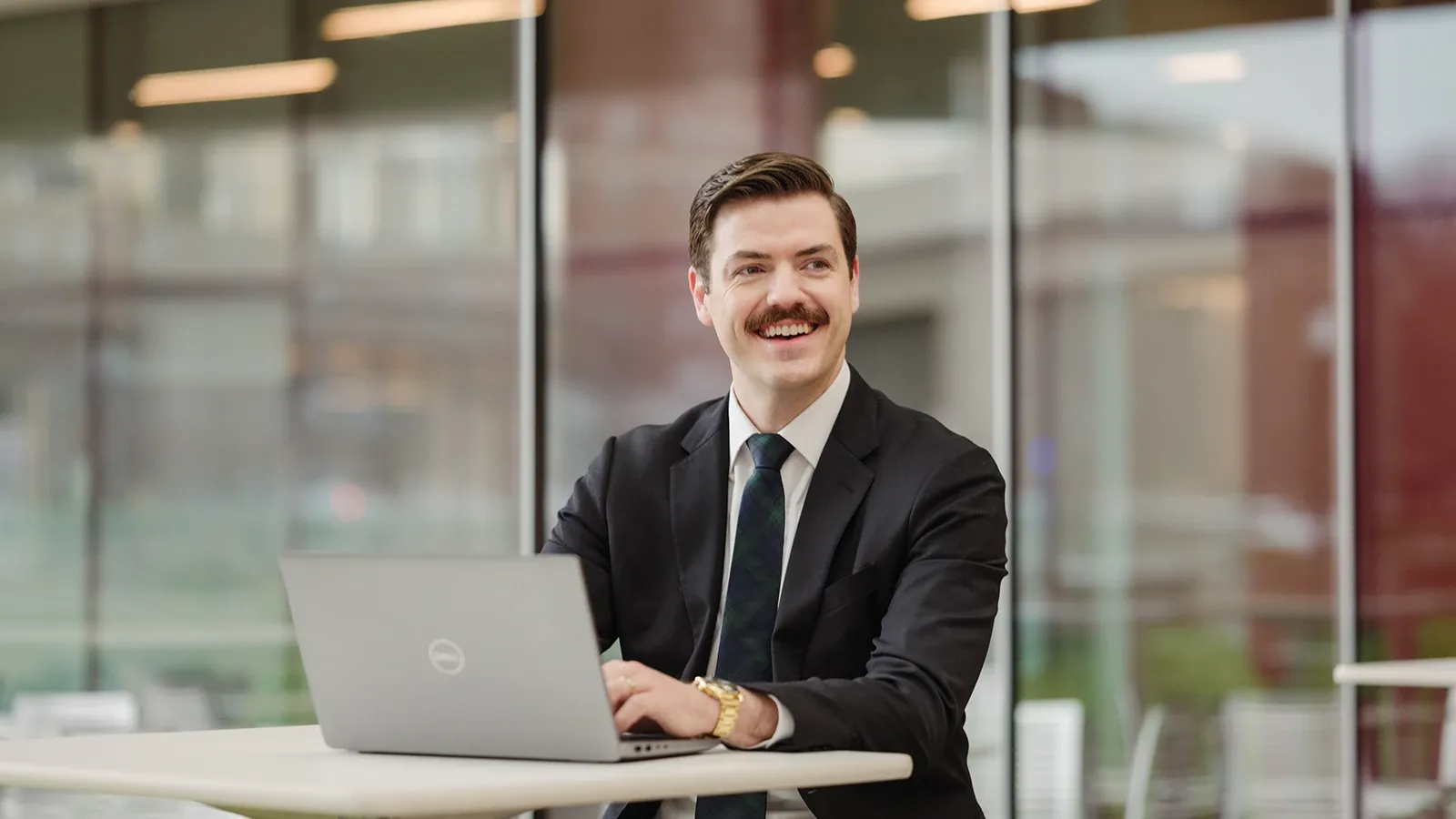 A Tepper School student sitting at a table with laptop computer.