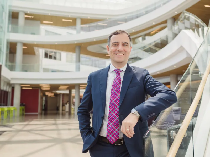 A photo of Laurence Ales standing in the Atrium of the Tepper School building