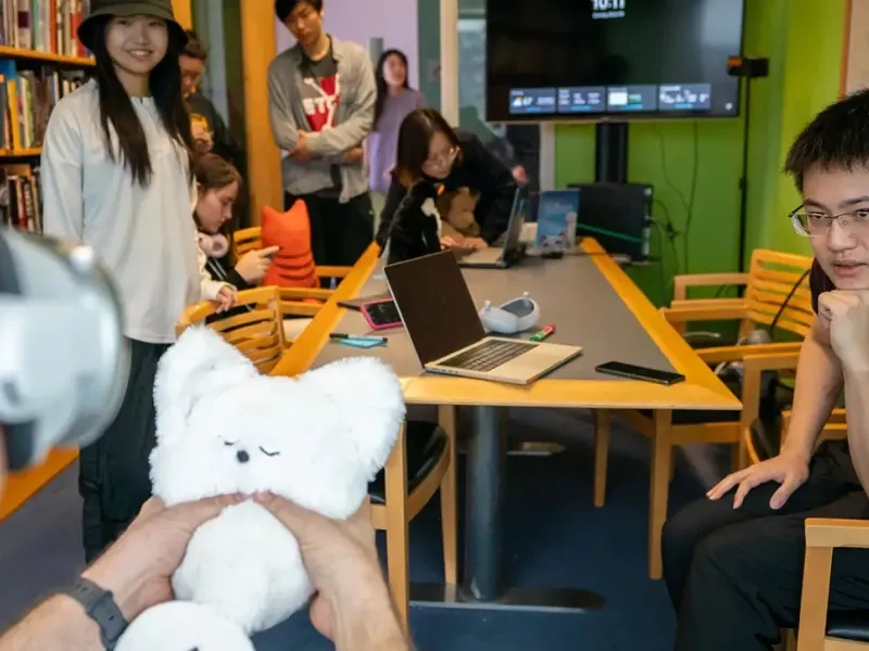 The Physical Presence Pet team looks on while a guest playtests their project.