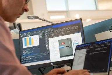 Man looking at a computer screen and a mobile phone