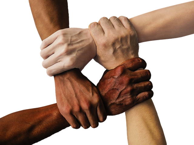 A group of diverse hands are clasped together in a group.