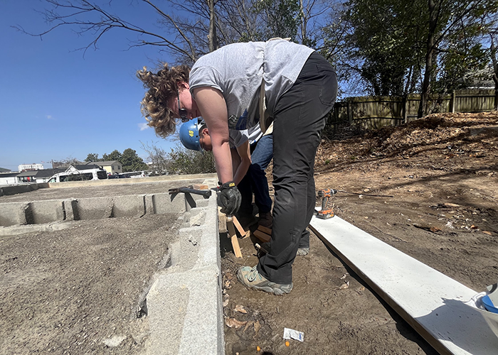 a CMU student building the foundation for a home with concrete blocks