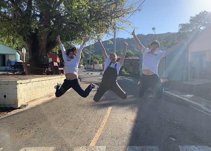 three students jumping for joy in the sunshine