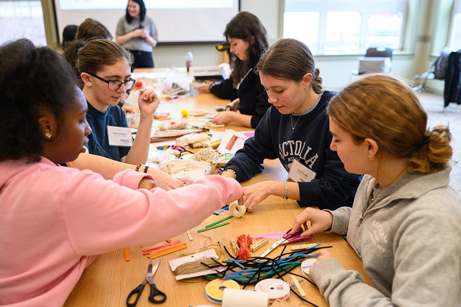 CMU students working with their hands at a table during a leadership retreat