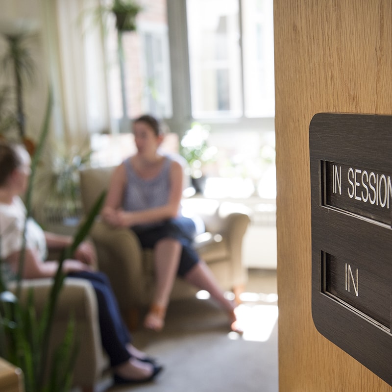 Photo from a distance of a counseling session, with the counselor and the patient blurred