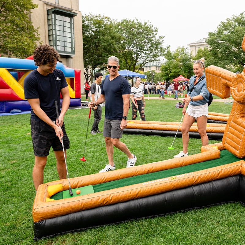 A CMU student and his family play pop-up miniature golf on the Cut.