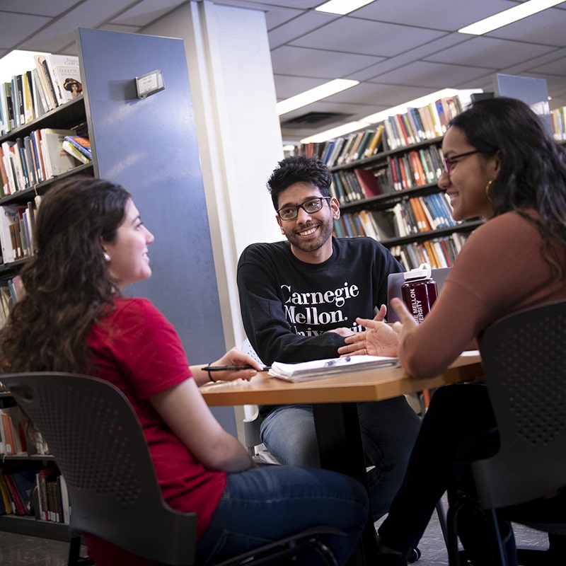 three students sitting together in the library 