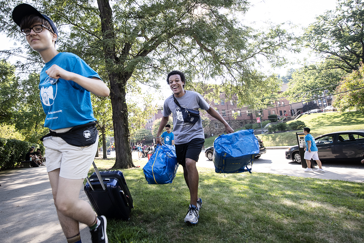 Image of students carrying luggage into dorm on move-in day