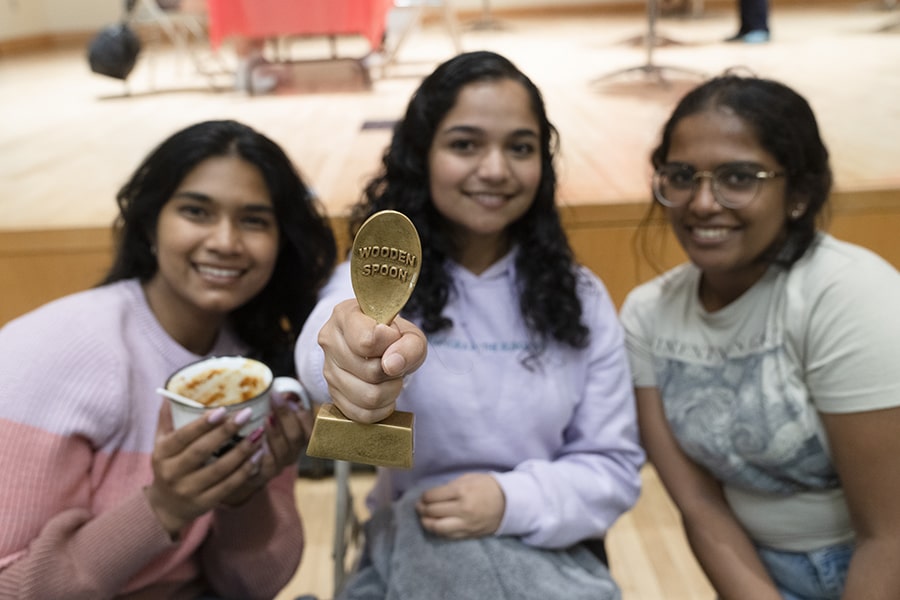 Three CMU students holding a wooden spoon trophy at the Chili Cook-Off