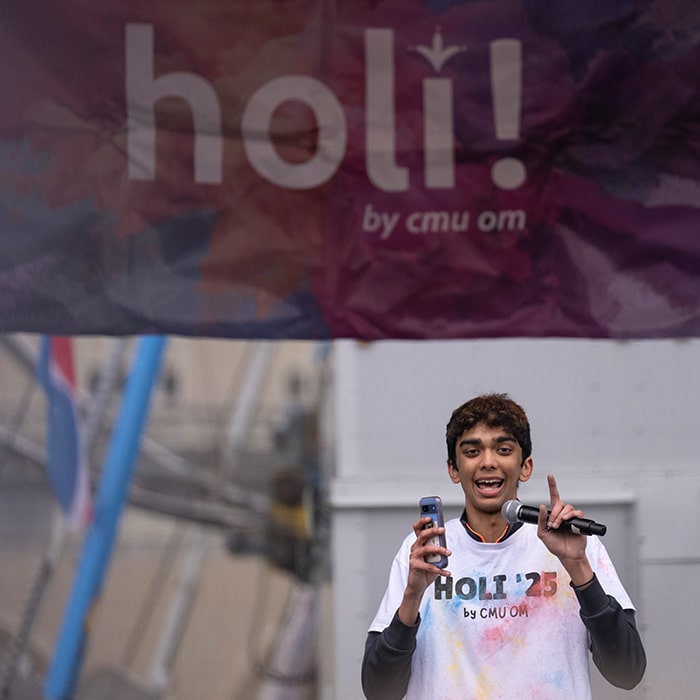 Student from CMU Om shouts out on a microphone during CMU Holi 2025