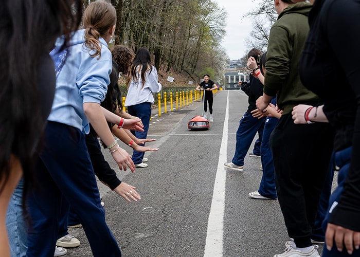 Team members make a tunnel to cheer on a buggy driver and pusher at Sweepstakes