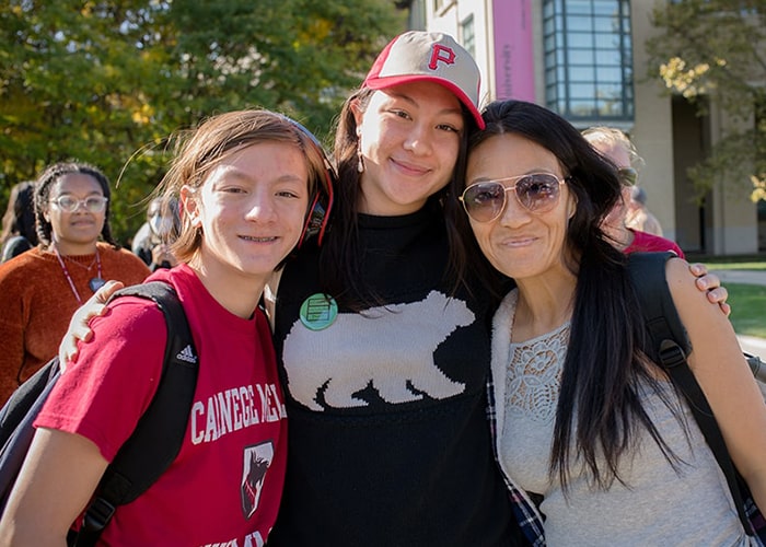Three family members smiling for the camera dressed in CMU gear during Family Weekend