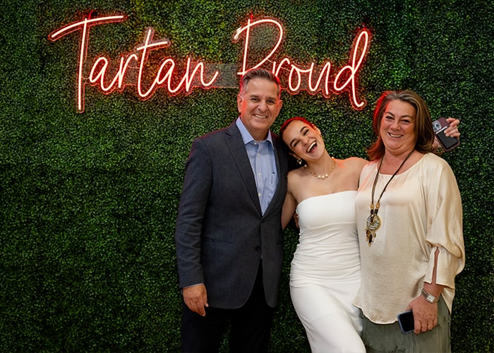Honored student poses with her family in front of the Tartan Proud wall