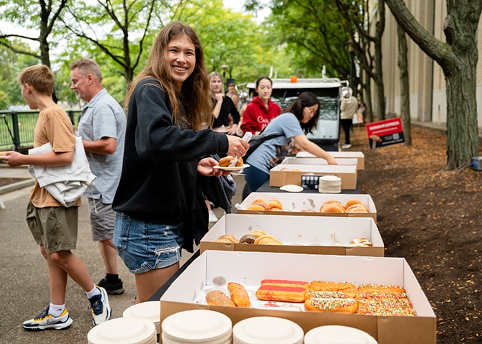 A student smiles as she grabs a yummy donut on the East West Walkway during Scotty Saturday