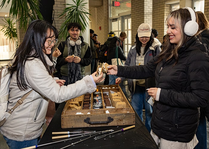 Students "cheers" their s'mores together in Kirr Commons during a Winter Welcome S'mores-making event.