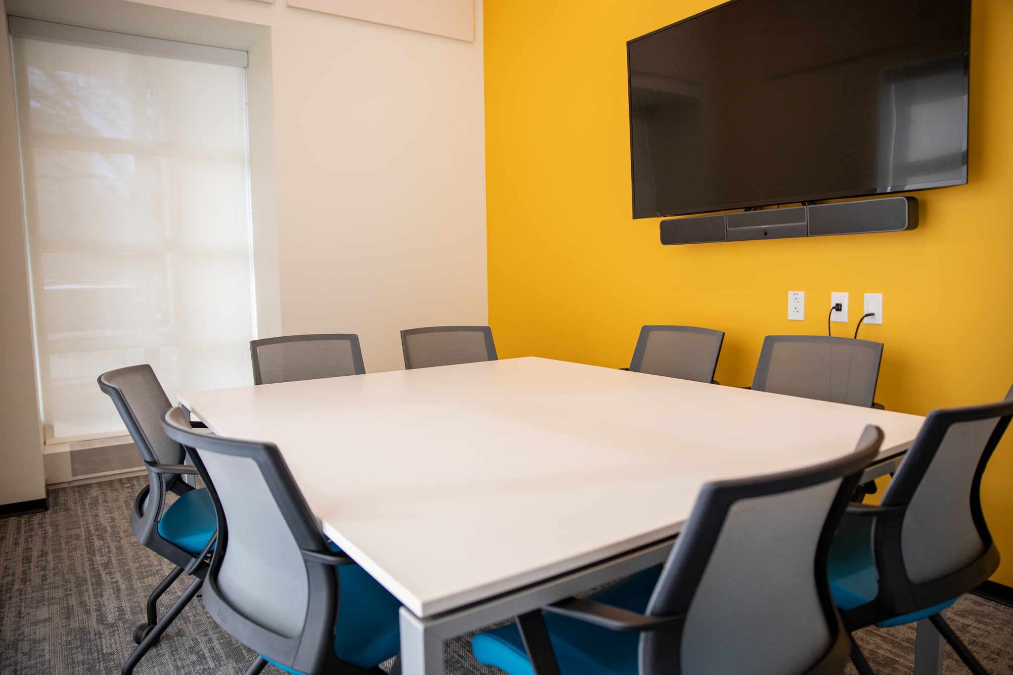 table and chairs, a digital display in front of a yellow wall