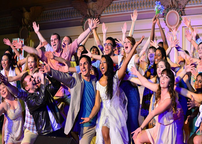 Students raising hands up for Greek Sing