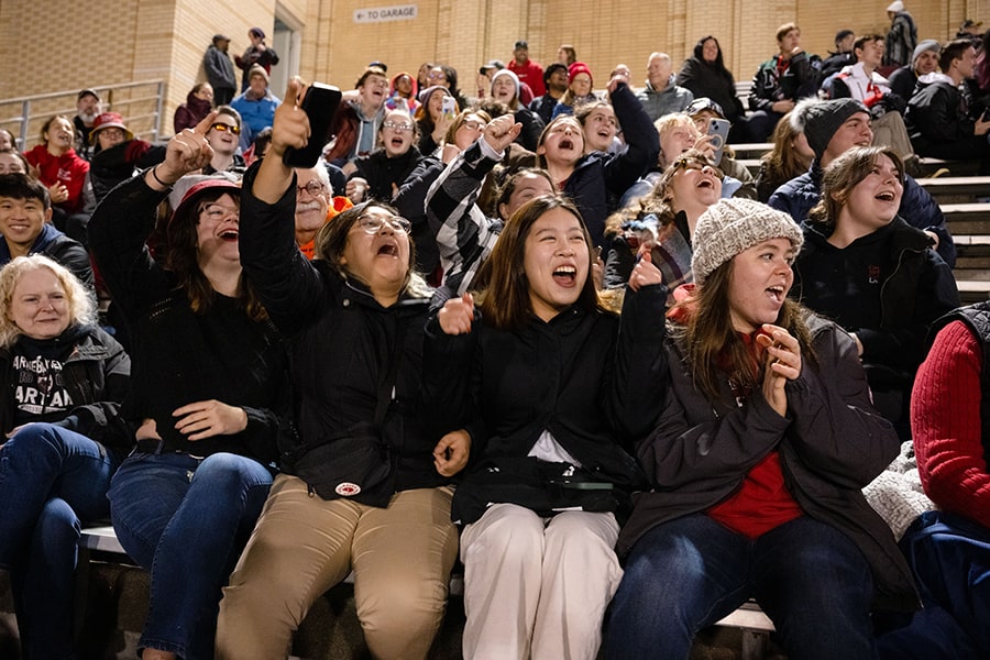 students and families sitting in the bleachers during a football game cheering