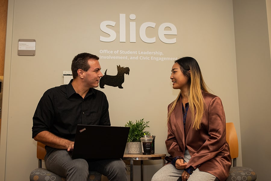 a SLICE staff member with a student under a SLICE sign